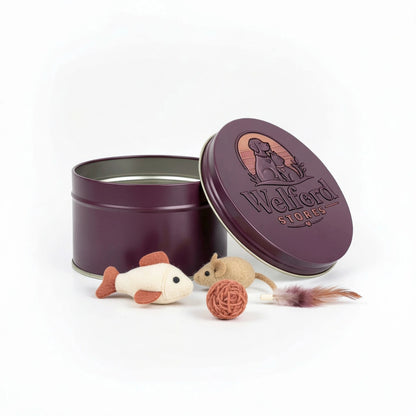 Open plum Welford Encore tin for cats with felt fish, felt mouse, woven ball and feather lure on a white background